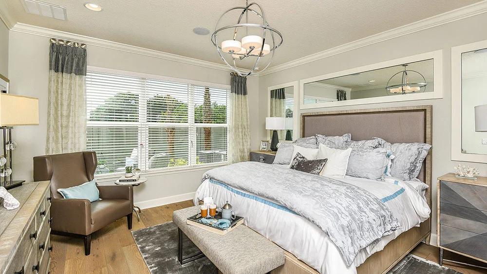 First-floor primary suite in the Anastasia model with tray ceiling and garden views
